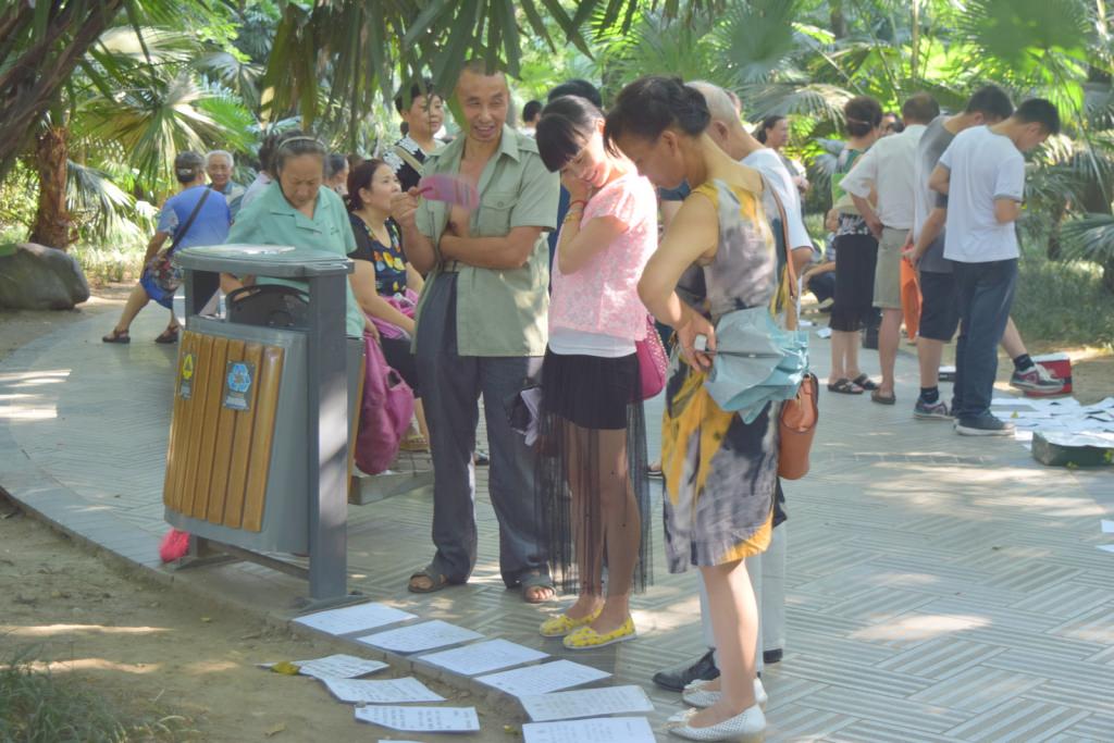 עוברי אורח בודקים את המודעות בפארק העם בצ'נגדו (צילום: טל ניצן)